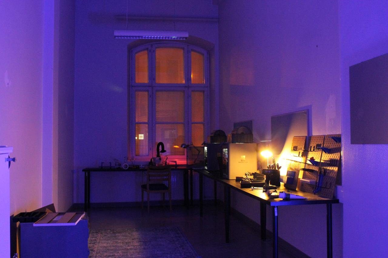 The STUHI hardware lab lit in purple: workbenches with tools, electronics and a lit-up window